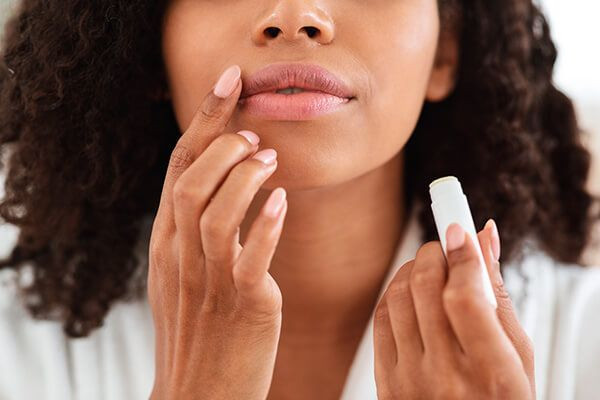 mulher aplicando hidratante labial com manteiga de karité.