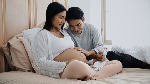 mulher grávida e homem acariciando a barriga da gestante.